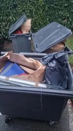 Bac au couvercle ouvert rempli de cartons non aplatis sur le point de collecte